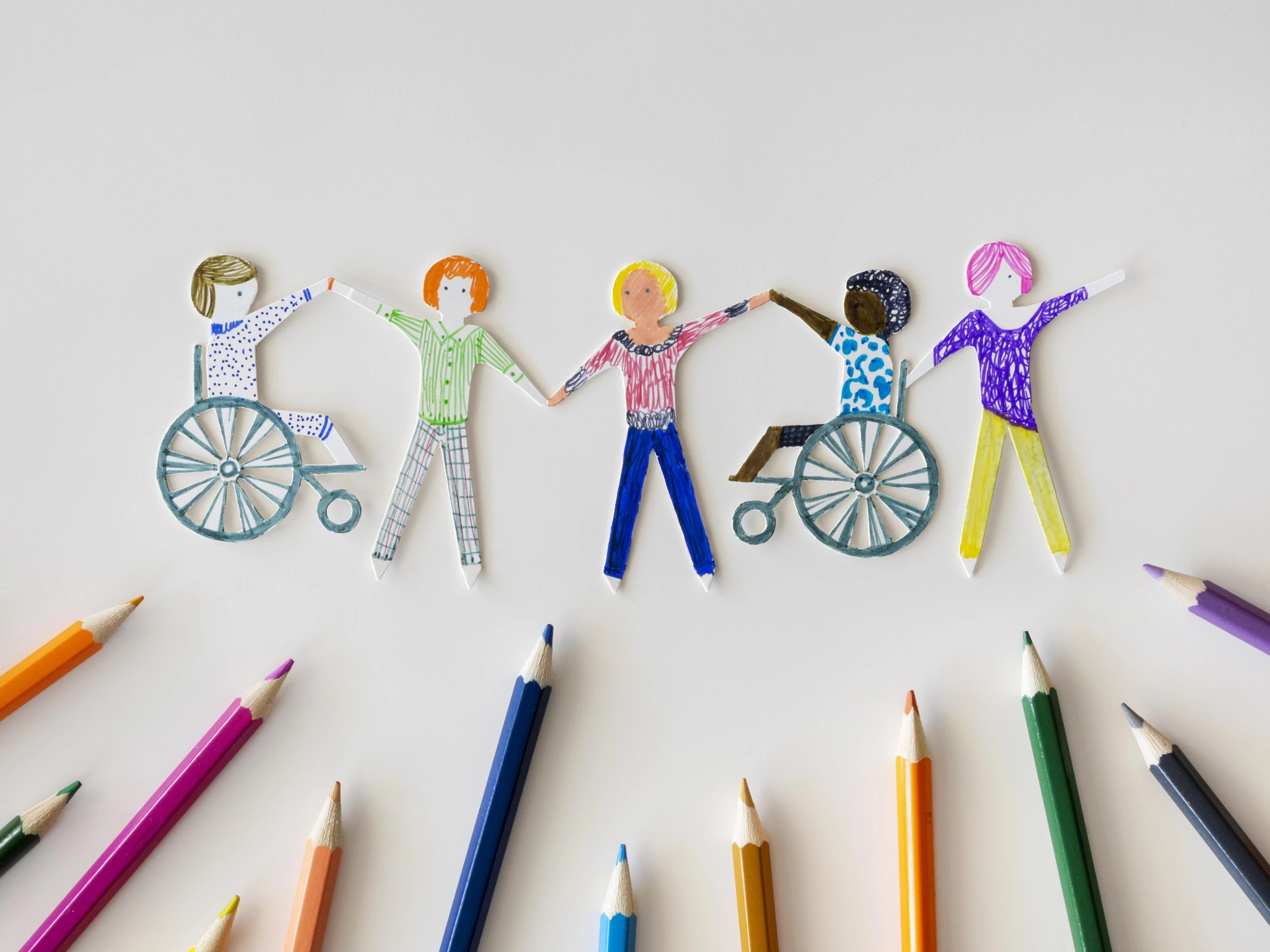 Cut-outs of multi-ethnic and disabled people with colored pencils.