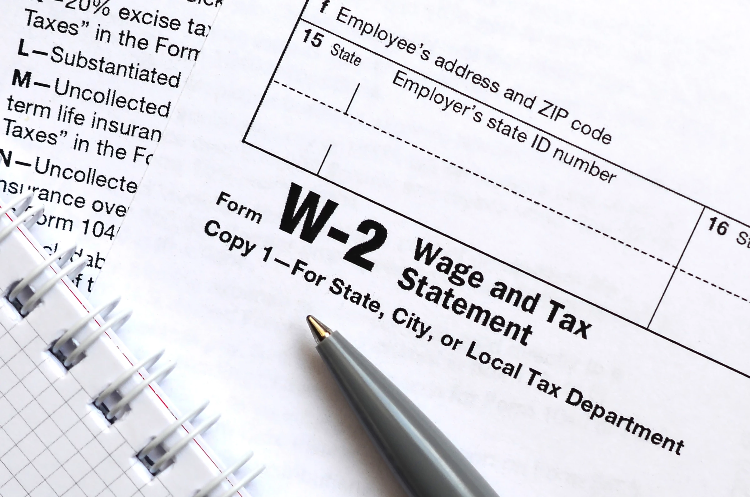 A pen and notebook on top of tax form W-2 Wage and Tax Statement