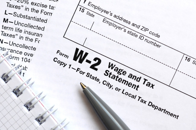 A pen and notebook on top of tax form W-2 Wage and Tax Statement