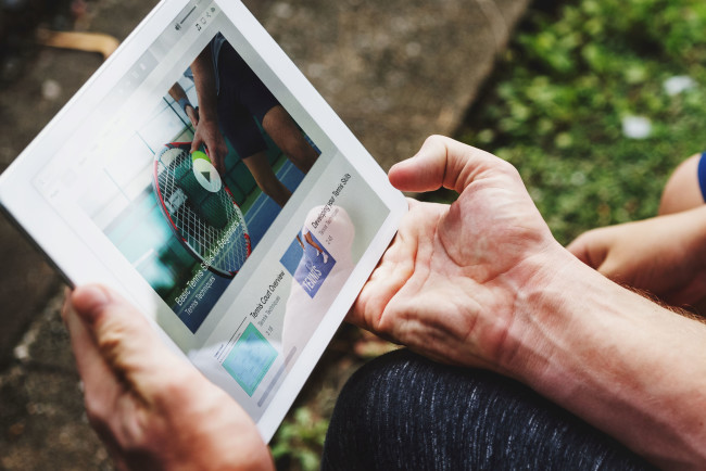 A man reads a company newsletter from a tablet