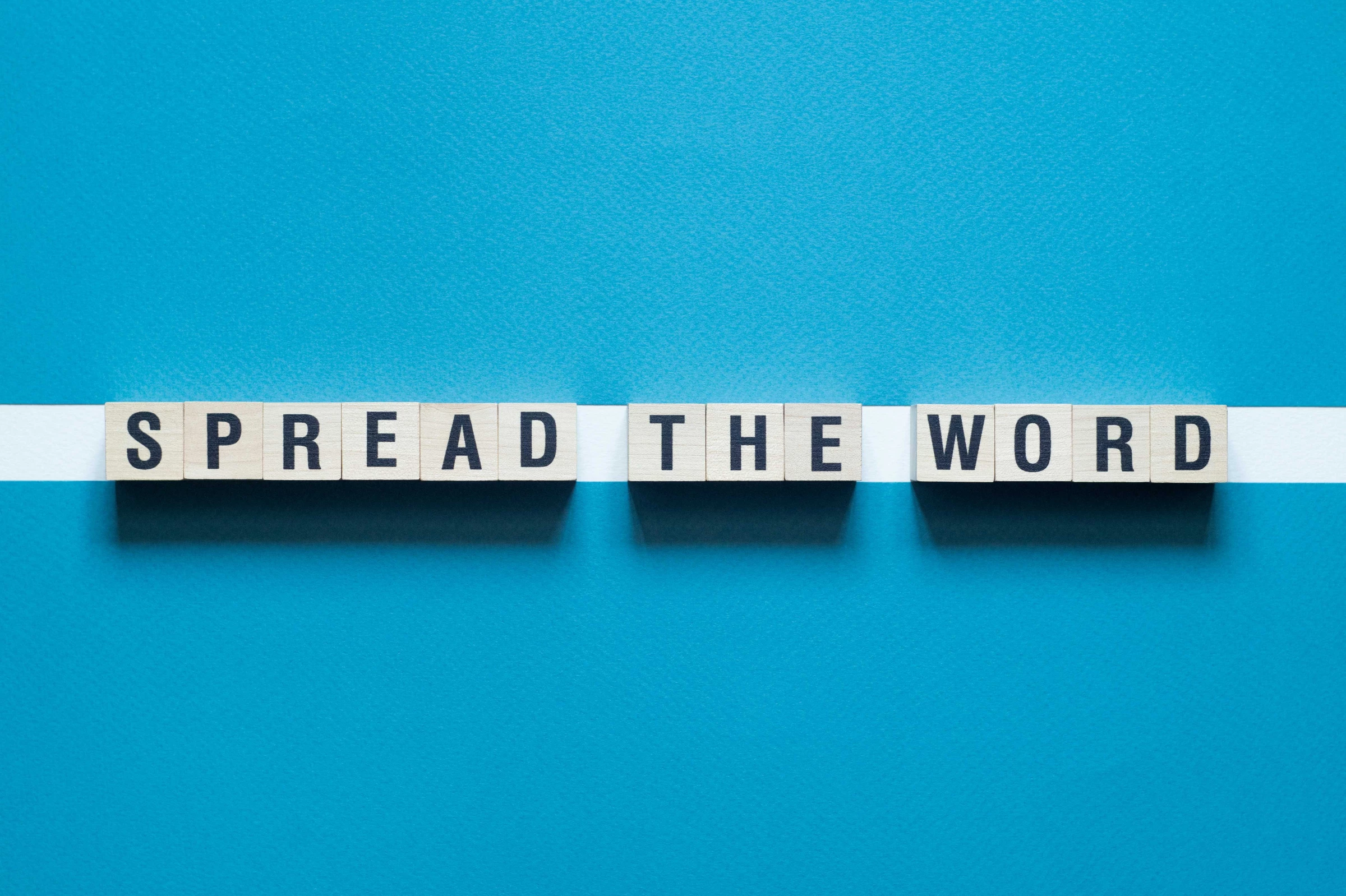 The words ”spread the word” on wooden tiles