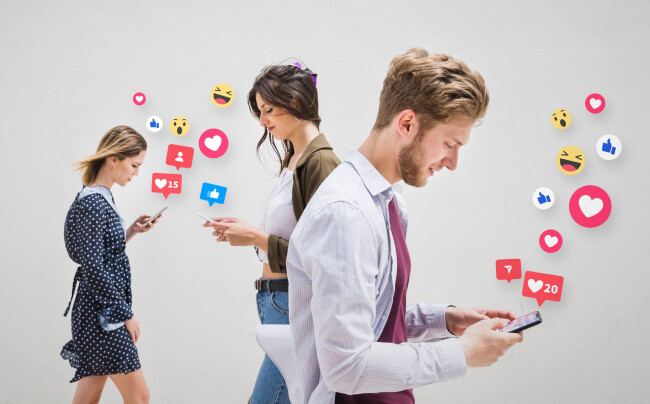 People using smartphones with social media reaction icons floating around them