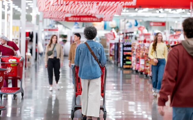 Shopper pushing a cart through a busy, festive Target store aisle