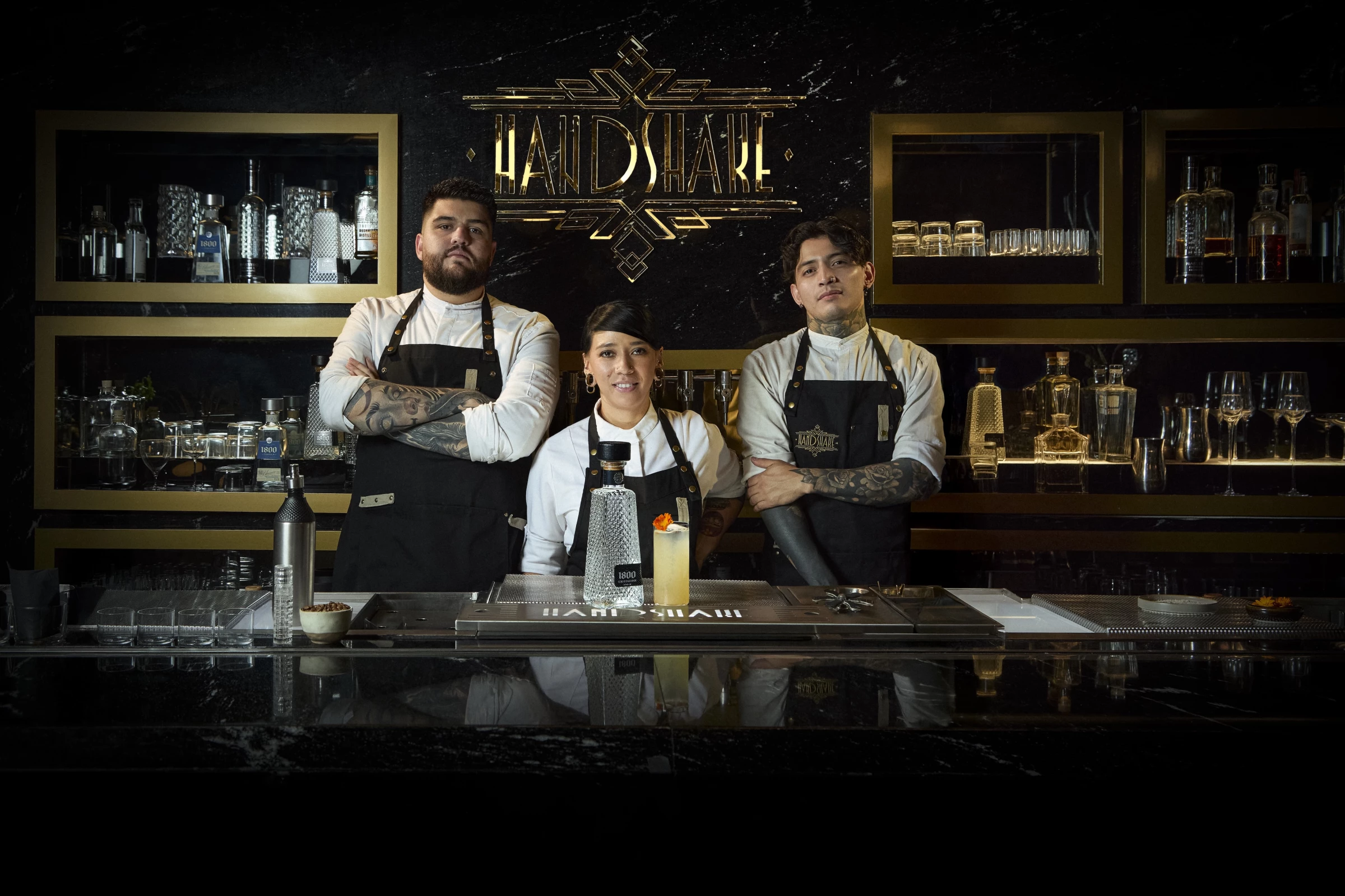 Three top bartenders pose with the signature cocktail made with 1800 Tequila at Handshake Speakeasy.