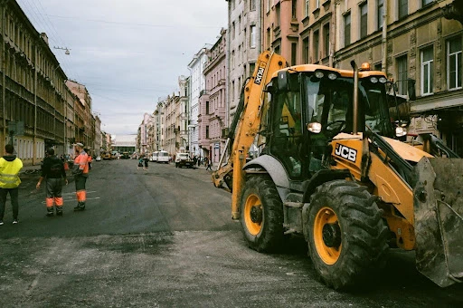 Construction workers next to an excavator in the street