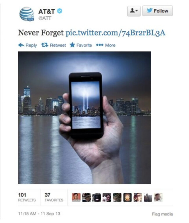 Screenshot of a 2013 tweet by AT&T featuring the message "Never Forget" with a link. The image in the tweet shows a hand holding a smartphone, which displays the Tribute in Light memorial in New York City, symbolizing the Twin Towers. The phone is centered against the city skyline at night, with the memorial lights visible both on the phone screen and in the background. Ask ChatGPT