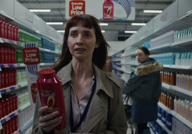 A woman holding L'Oreal shampoo in Tesco's Ad | Source: Tesco