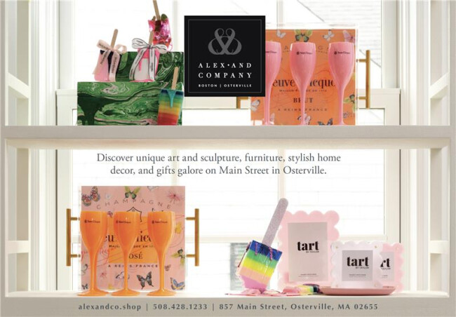 Window display for Alex & Company featuring colorful luxury home decor, Veuve Clicquot gift sets, and Tart by Taylor products, highlighting the brand’s upscale retail identity in Osterville.